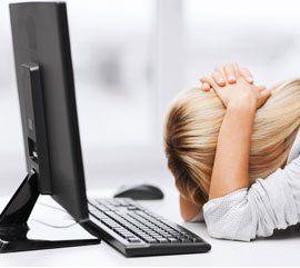 en kvinde der tager sig til hovedet på grund af computer problemer